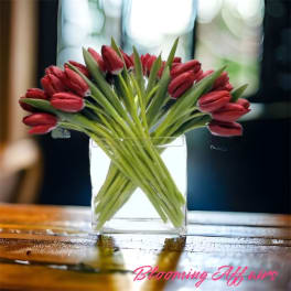 Red tulips arranged in a clear glass vase