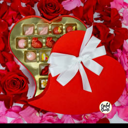 Heart-shaped gift box of chocolates on a bed of rose petals