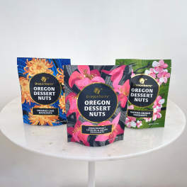 Three bags of Oregon Dessert Nuts on a round white table
