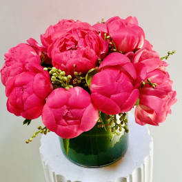 Bright pink peony bouquet in a green glass vase