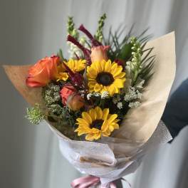 Hand-tied bouquet with a sunflower, blue flowers, and pink blooms