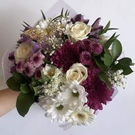 Handheld bouquet of white, purple, and pink flowers with a butterfly pick