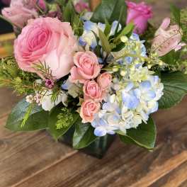 Pink roses and blue-white hydrangeas in a glass vase