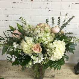 Large bouquet of pale hydrangeas and blush roses in a glass vase