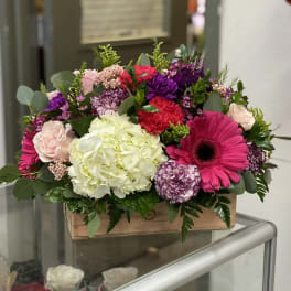 Mixed bouquet in a wooden box with pink, purple, white, and red flowers