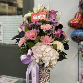Pink and white mixed bouquet in a patterned vase with a lavender ribbon