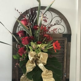 Tall tropical bouquet with red roses, green orchids, and a gold ribbon in a vase
