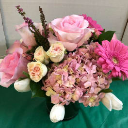 Pink roses and hydrangea in a black vase with a pink gerbera daisy