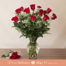 Red roses arranged in a clear glass vase with a matching rose boutonniere.