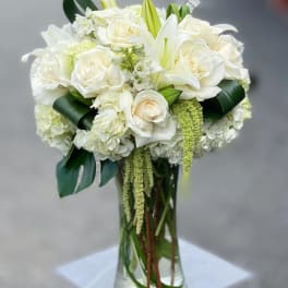 White roses and lilies arranged in a clear glass vase