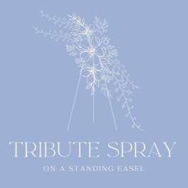 White floral tribute spray on a standing easel against a blue background