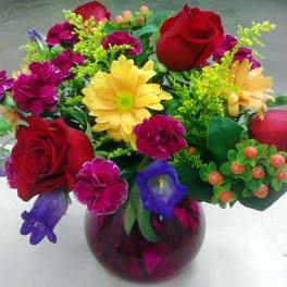 Mixed bouquet in a purple glass vase with red roses and yellow daisies