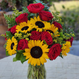 Bouquet of red roses and yellow sunflowers in a glass vase