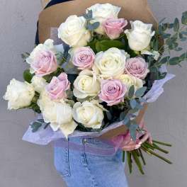 Large hand-tied bouquet of white and pale pink roses wrapped in kraft paper, held by a person.