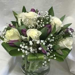 Bouquet of white roses and purple tulips in a glass vase