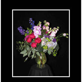 Mixed bouquet of pink, purple, and blue flowers in a clear glass vase