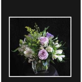 Lavender roses and white lilies in a clear glass vase