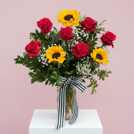 Bouquet of red roses and yellow sunflowers in a glass vase