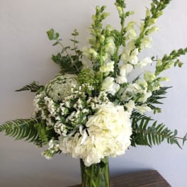 White flowers and greenery arranged in a clear glass vase