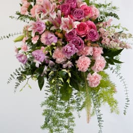 Pink and purple floral spray on a stand with trailing greenery
