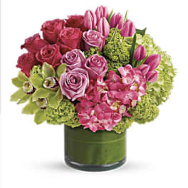 Pink roses and tulips arranged in a green glass vase