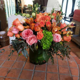 Large bouquet of peach and pink roses with orange orchids in a vase