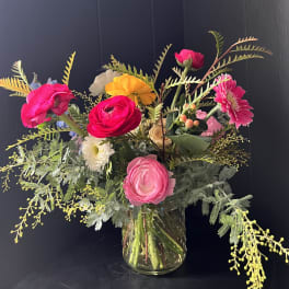 Bright mixed bouquet in a clear glass vase with pink, yellow, and white blooms