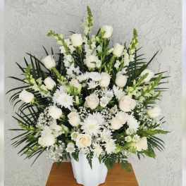 White roses and daisies arranged in a white vase