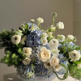 Blue hydrangea and white flower arrangement in a white vase