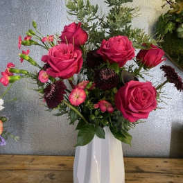 Pink roses and small accent flowers in a white vase