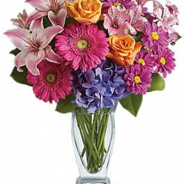 Mixed bouquet of pink lilies, roses, gerbera daisies, and hydrangea in a glass vase