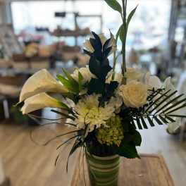 White calla lilies and roses arranged in a green striped vase