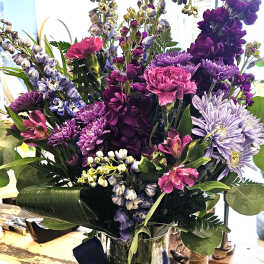 Purple and pink mixed bouquet in a glass vase with a navy ribbon