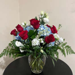 Red roses and blue hydrangeas in a clear glass vase