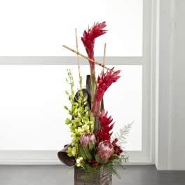 Tall tropical arrangement with red blooms in a wooden cube vase