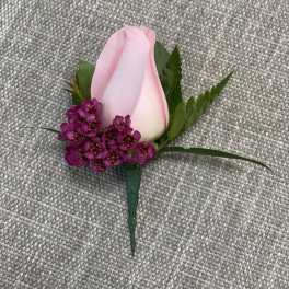 Pink rose boutonniere with small purple accent flowers