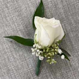 White rose boutonniere with small white filler flowers and green leaves