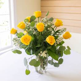 Yellow roses in a clear glass vase with small white filler flowers
