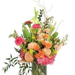 Mixed bouquet of peach, pink, and orange flowers in a glass vase