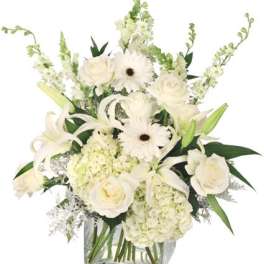 White roses, lilies, gerbera daisies, and hydrangeas in a clear glass vase