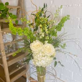 White roses and hydrangeas in a clear vase with green accents