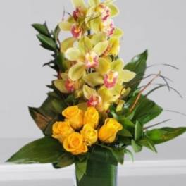 Yellow orchids and roses in a square glass vase