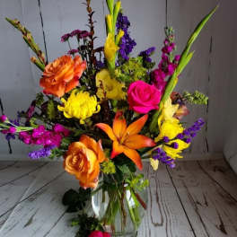 Colorful mixed bouquet in a clear glass vase with roses and lilies