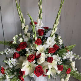 Red and white floral arrangement in a white pedestal vase