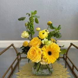 Yellow roses and a gerbera daisy in a glass vase