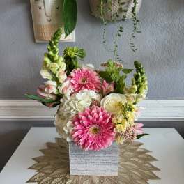 Pink and white flowers arranged in a square gray vase