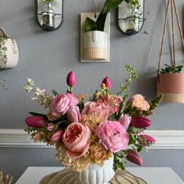 Pink and peach floral arrangement in a white vase