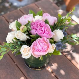 Pink peonies and white roses arranged in a low vase