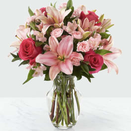 Pink lilies, roses, and carnations in a clear glass vase