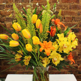 Mixed bouquet of yellow and orange flowers in a clear glass vase